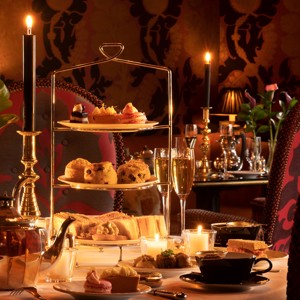 Rhurbarb Edinburgh restaurant table set for afternoon tea with a three-tier stand of pastries, scones, and sandwiches, teapot, teacups, champagne glasses, candles, and flowers