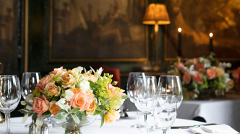 Bouquet of flowers and wine glasses on table with paintings in Edinburgh restaurant private rooms