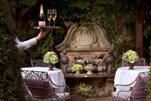 Waiter holds tray with champagne in the Prestonfield House' private dining space Garden Room's terrace 