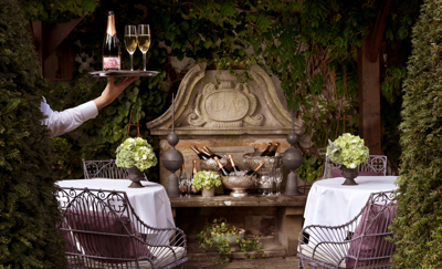 Waiter holds tray with champagne in the Prestonfield House' private dining space Garden Room's terrace 