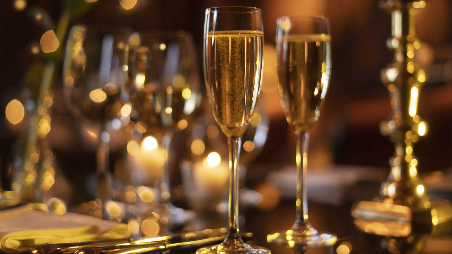 Champagne flutes filled with champagne, silver cutlery and candlesticks on a private dining room table in Prestonfield