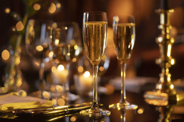 Champagne flutes filled with champagne, silver cutlery and candlesticks on a private dining room table in Prestonfield