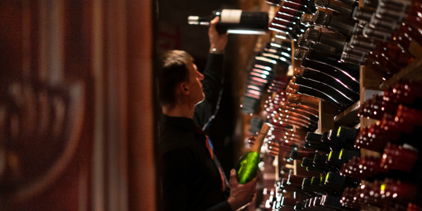 Wine racks and sommelier holding a bottle in the cellar at the Best Edinburgh restaurant for fine wines 