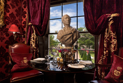Set table with marble bust and red velvet decor in The Salon Privee small private dining room at Prestonfield House Edinburgh